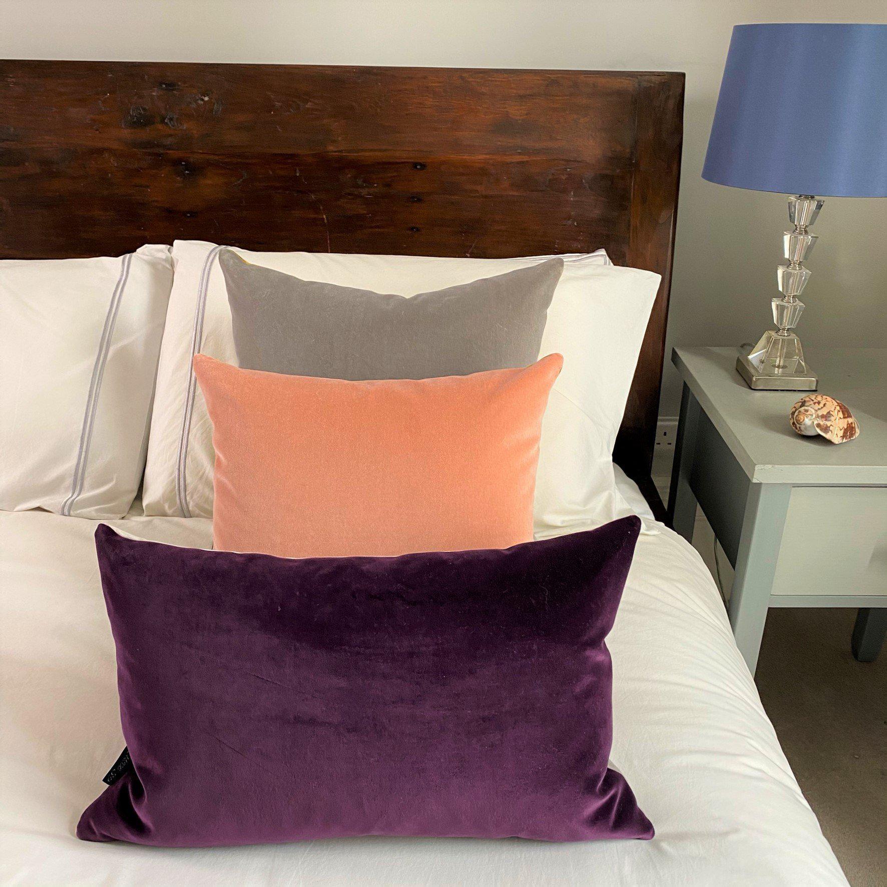 mauve cushion cover, blush cushion cover and grey cushion cover on a white bed
