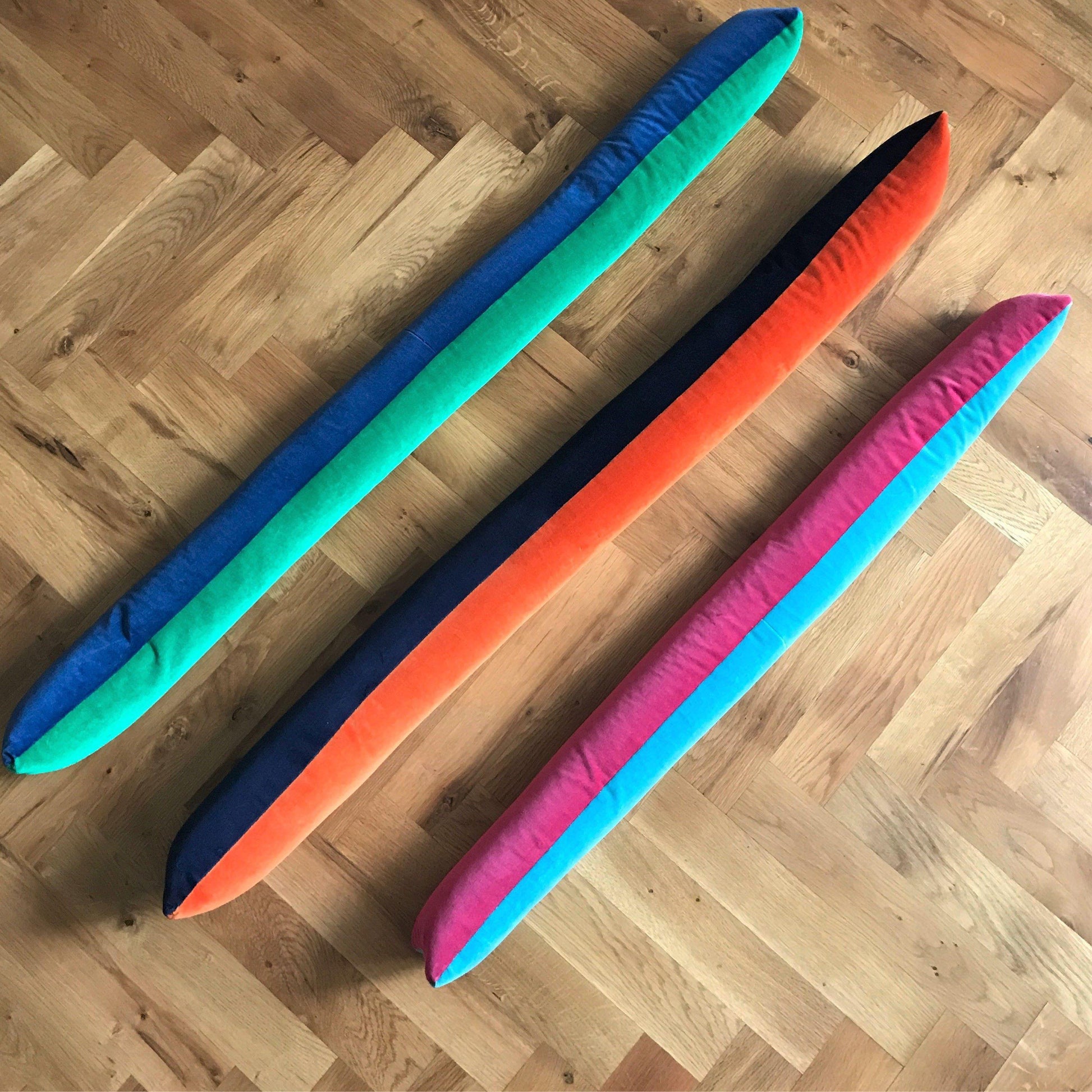 velvet draft excluders in bright pink, turquoise, orange, navy, green and royal blue