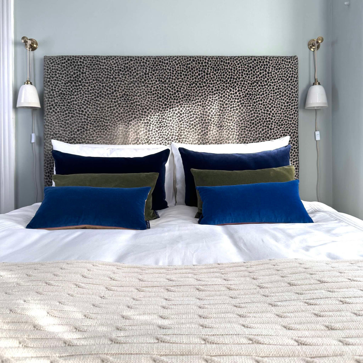 blue velvet cushions on white bedding in blue room