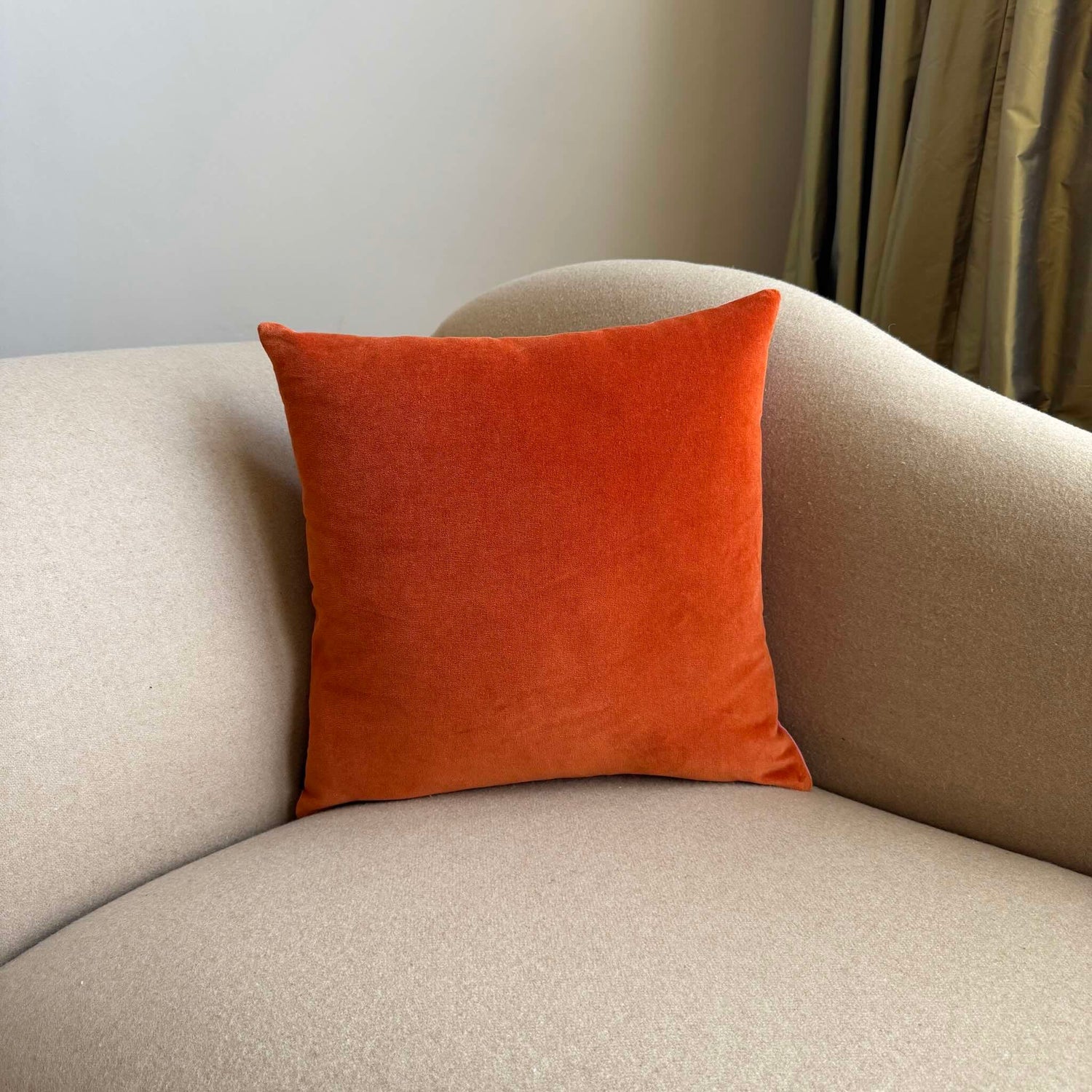 orange vevlet cushion on beige sofa