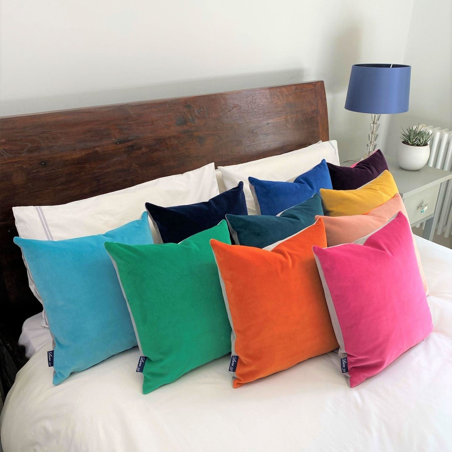 colourful velvet cushions lined up on white bedding