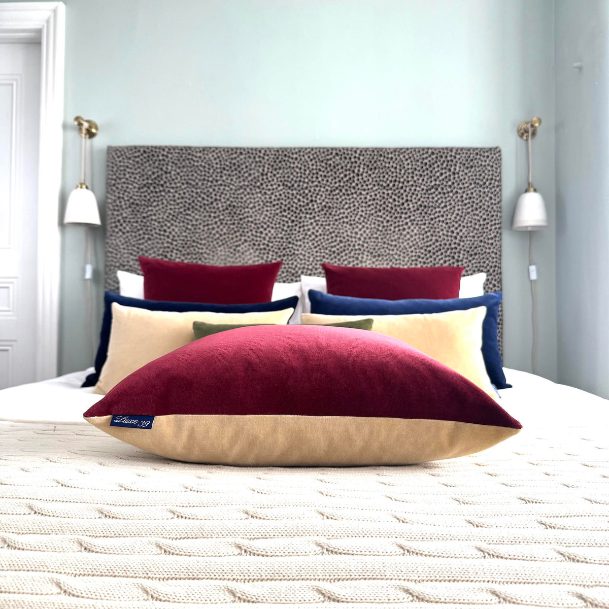 Burgundy and champagne velvet cushion side view in blue room