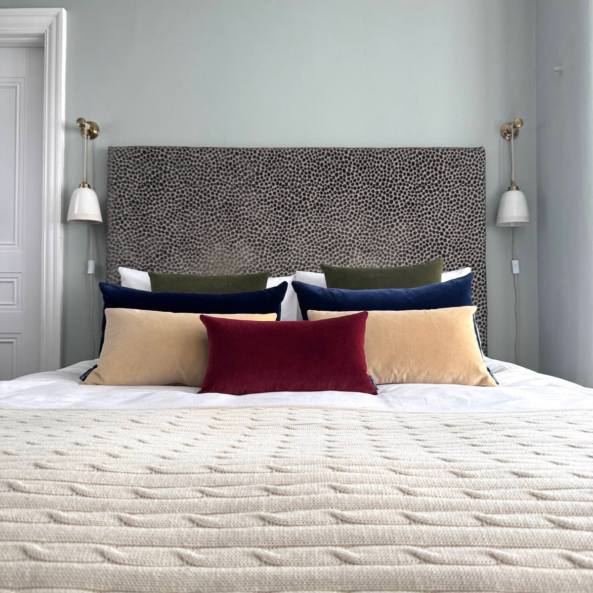 burgundy velvet cushion on a bed in a blue room