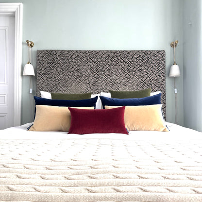 burgundy velvet rectangle cushion styled on a bed in a blue room
