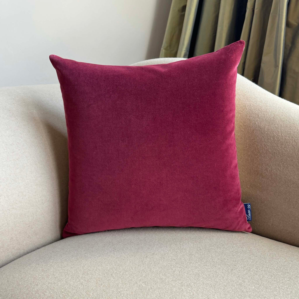 Burgundy velvet cushion square on beige sofa