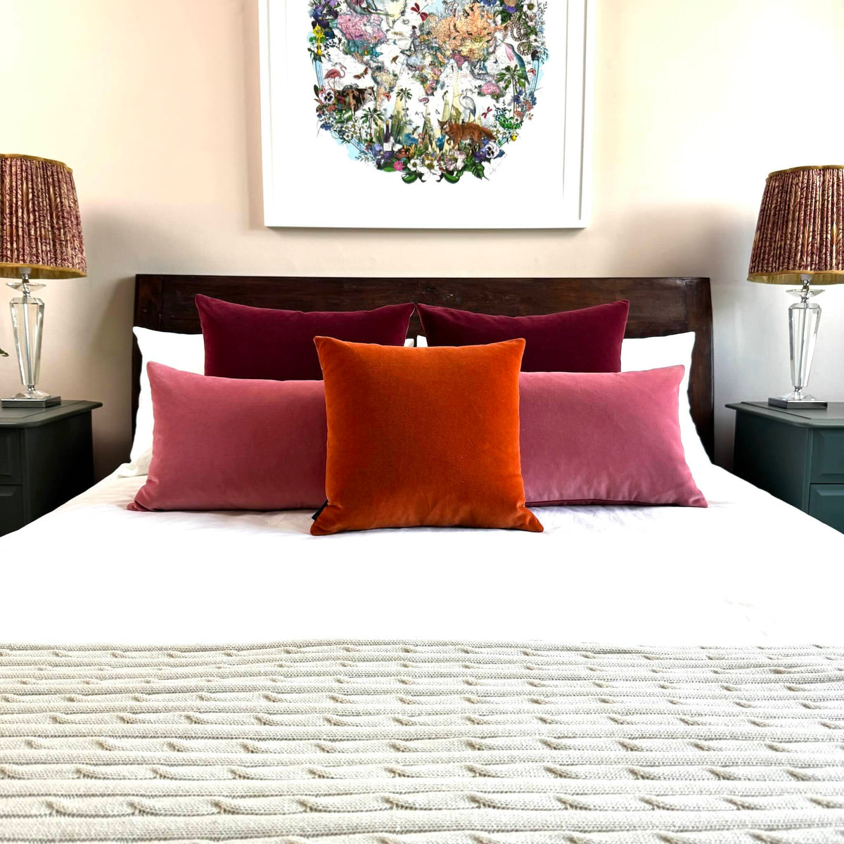 burnt orange velvet cushion with rouge pink and burgundy cushions on wooden bed