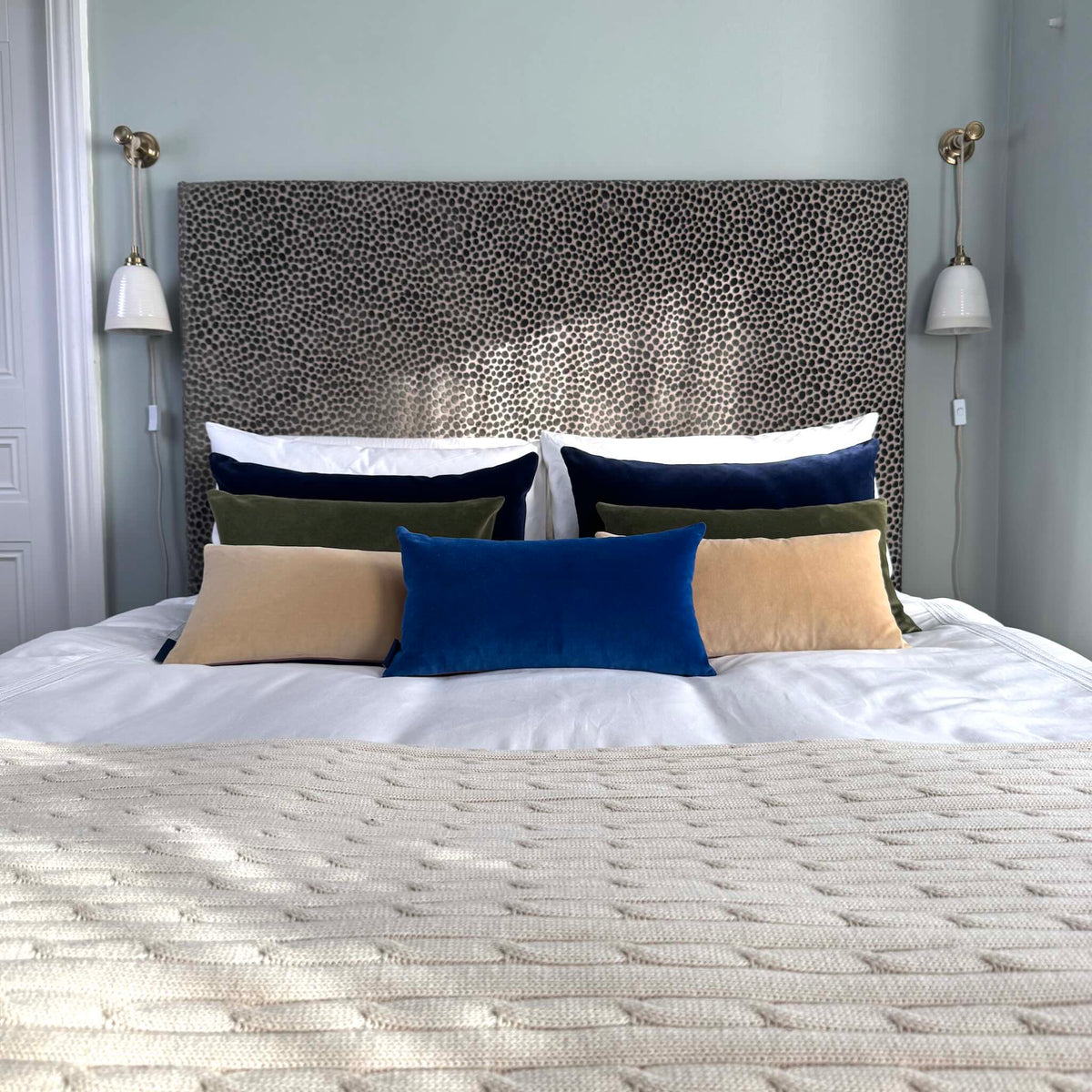 champagne cream velvet cushion on white bedding with cobalt cushions