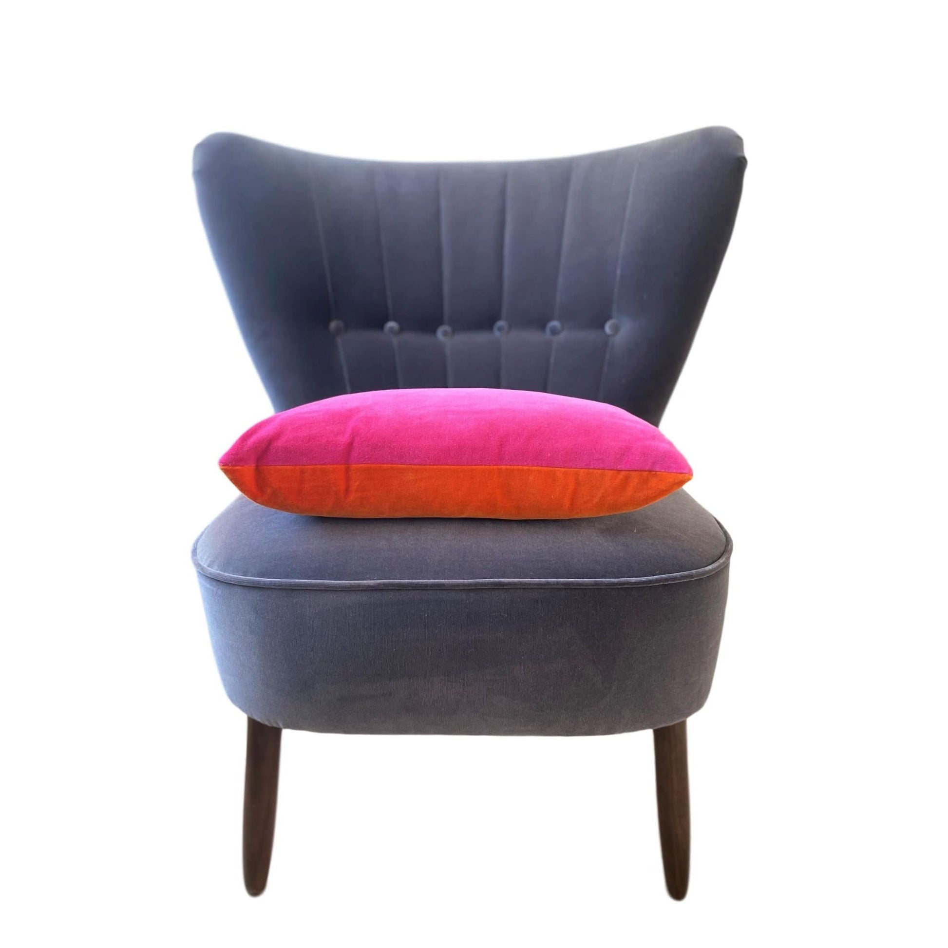 bright pink and burnt orange reversible velvet cushion on a dark grey velvet chair