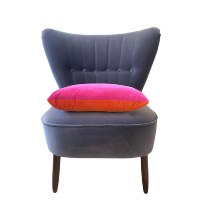 bright pink and burnt orange reversible velvet cushion on a dark grey velvet chair