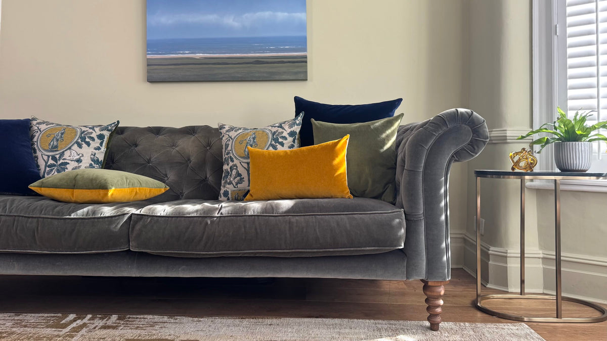 velvet cushions in gold ochre, olive and navy on a grey velvet sofa