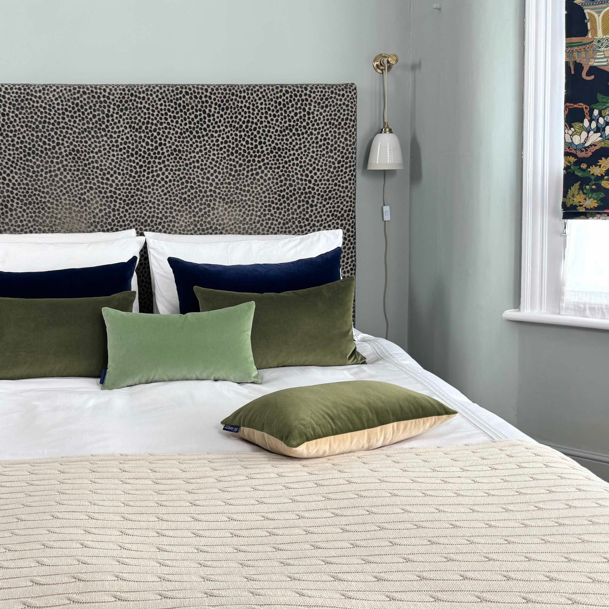olive green velvet cushion on white bedding in blue room