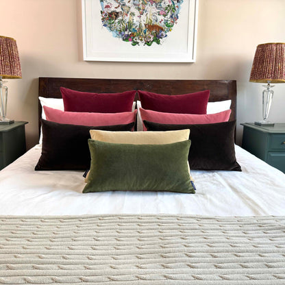 olive green velvet cushion on wooden bed