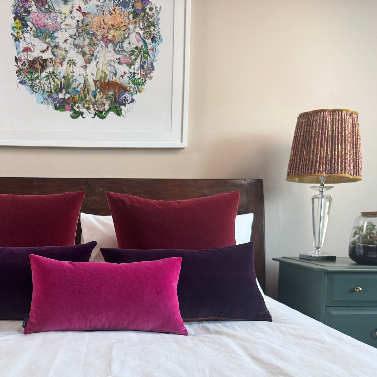plum velvet cushion with bright pink and burgundy on wooden bed
