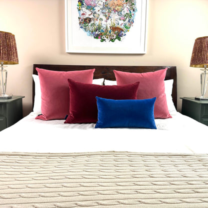 rouge pink velvet cushions styled on wooden bed with burgundy and cobalt cushions