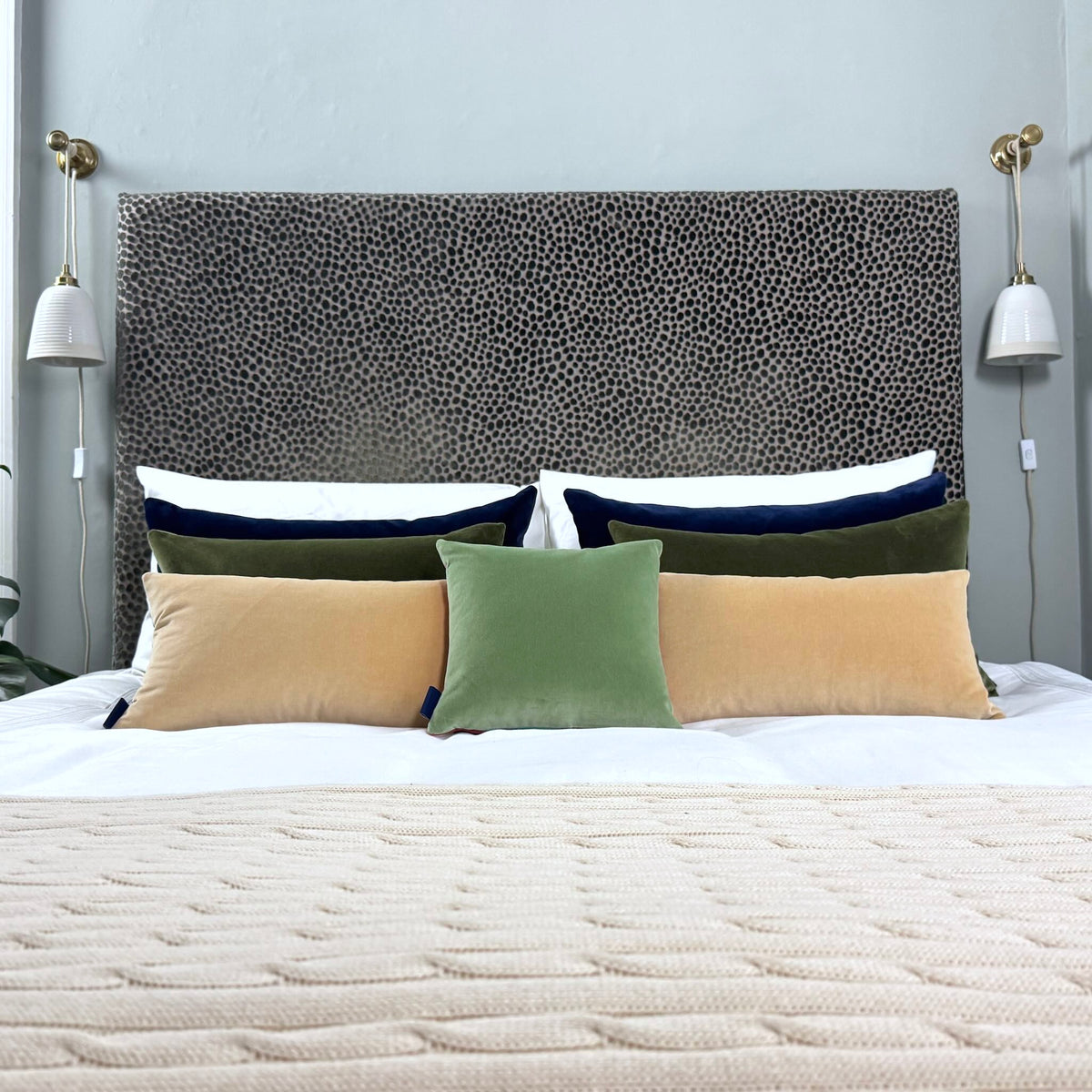 sage velvet cushion with champagne, olive and navy on white bedding in blue room