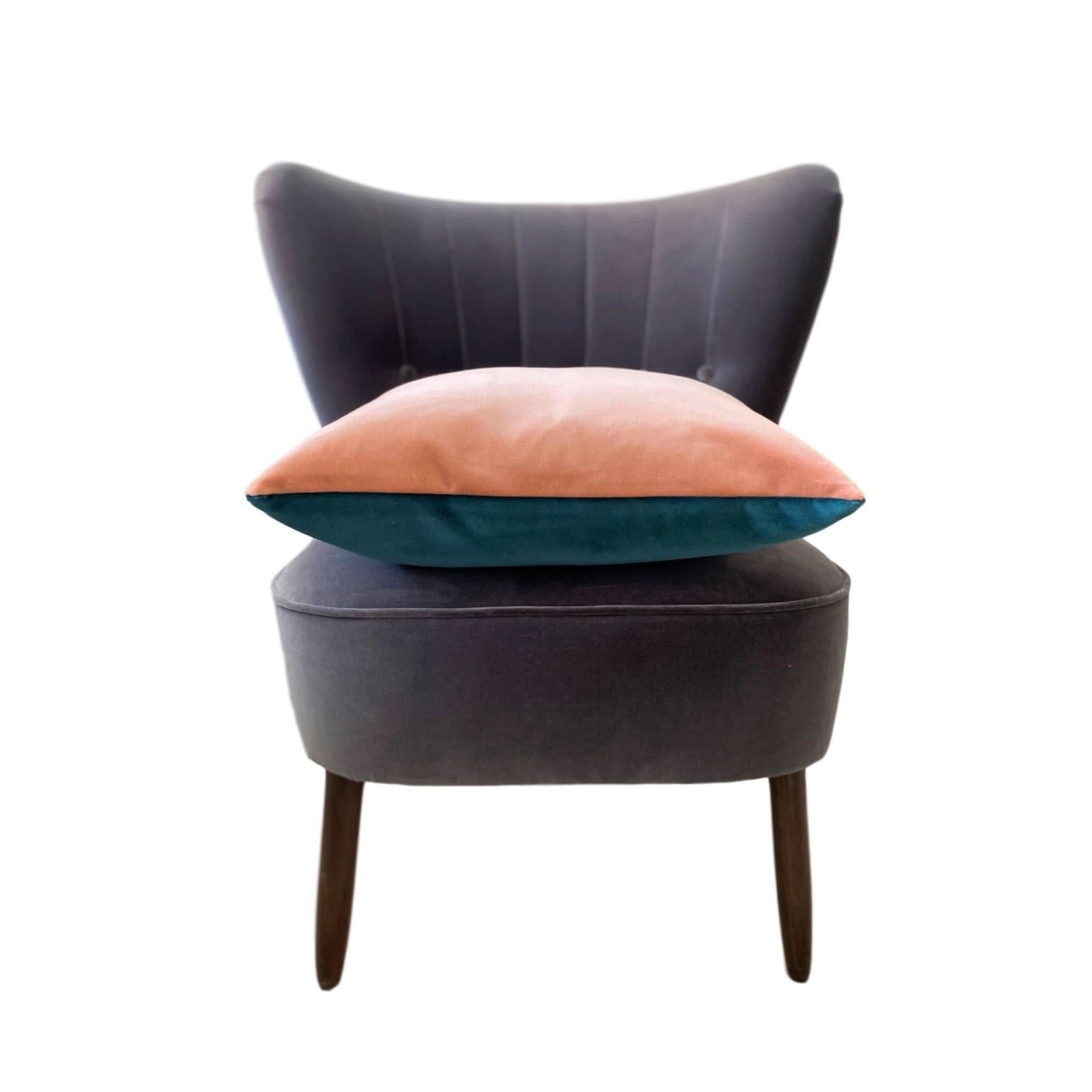 teal and pink cushion on a grey chair with a white background