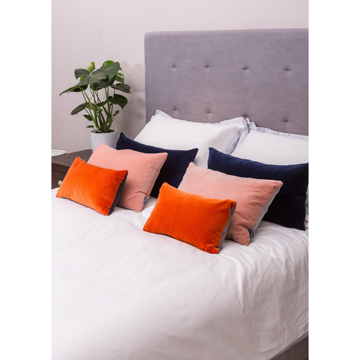 navy and burnt orange cushions with blush pink on a bed