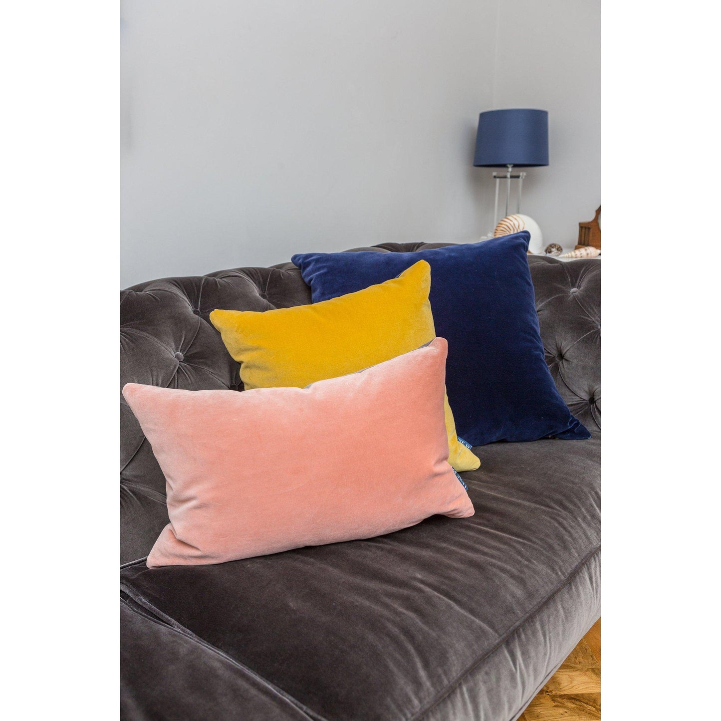 navy blue cushion cover with other colourful cushions on a velvet sofa