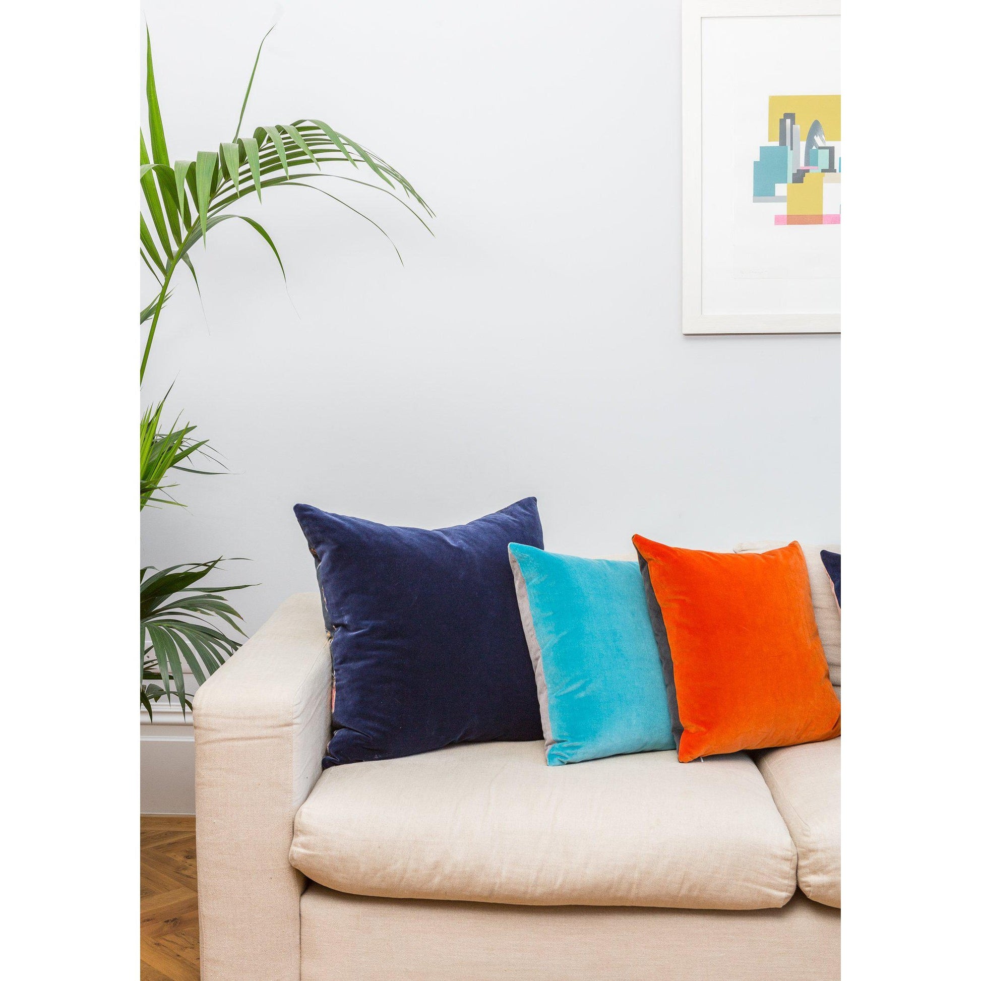 navy cushion cover with turquoise and orange cushions on a linen sofa