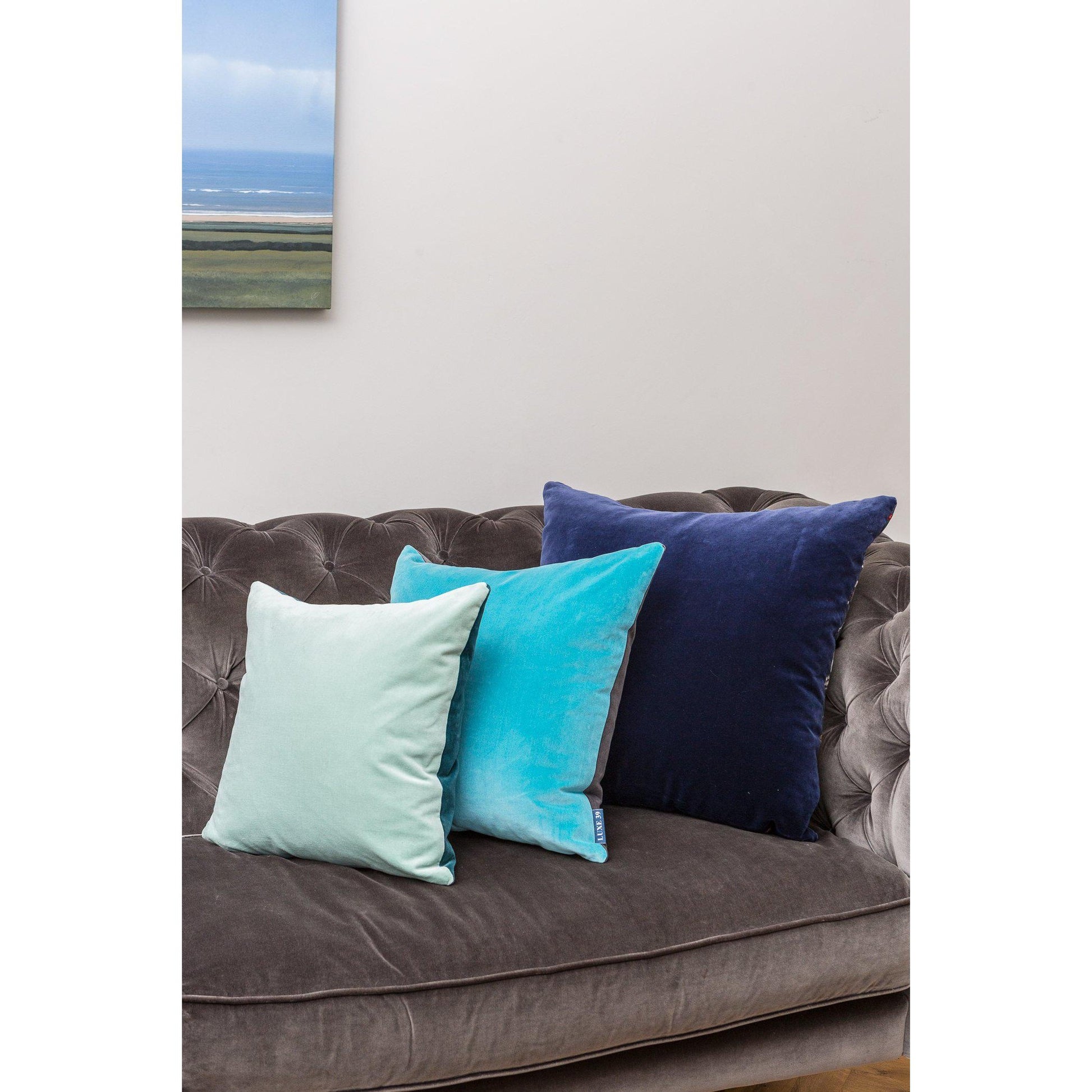 navy cushion cover with turquoise and duck egg on a velvet sofa